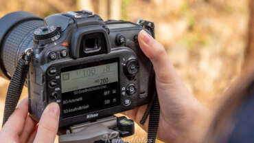 Eine Frau stellt den ISO-Wert an einer Nikon Spiegelreflexkamera über das Display auf ISO 200