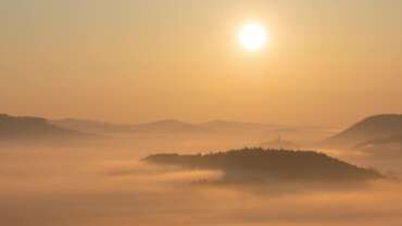 Ausschnitt aus einem Zeitraffervideo im Pfälzerwald, man sieht die aufgehende Sonne über Hügel und Bergen in der Pfalz mit nebelverhangenen Tälern