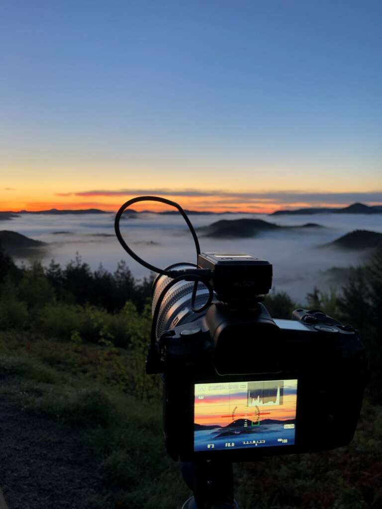Timelaps Setup, Kameraufaufbau für Zeitraffer-Aufnahmen: Kamera mit drahtlosem Fernauslöser im Pfälzerwald bei Sonnenaufgang mit Blick über die nebelverhangenen Täler