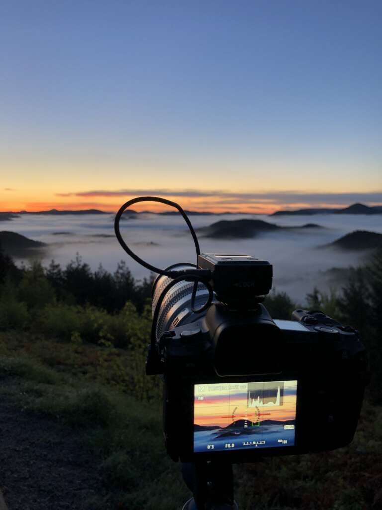 Eine Kamera von Stefan Engel steht auf einem Stativ an einem Aussichtspunkt im Pfälzerwald über dem Wolkenmeer. Die Kamera nimmt Bildserien für Timelapse auf.