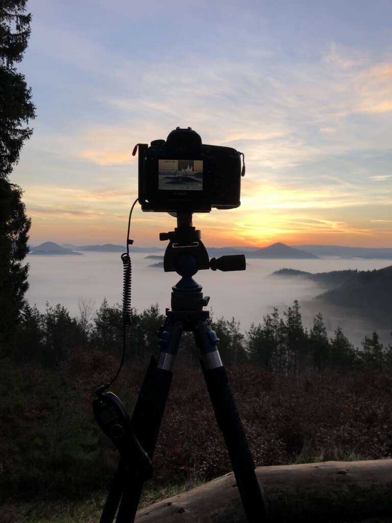 Eine Kamera von Stefan Engel steht auf einem Stativ an einem Aussichtspunkt im Pfälzerwald über dem Wolkenmeer. Die Kamera nimmt Bildserien für Timelapse auf.